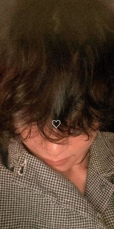 a close up of a person wearing a shirt with a heart pin in their hair