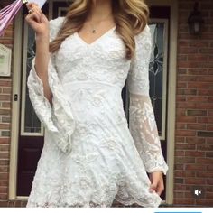 a woman in a white dress is holding a pink umbrella and posing for the camera