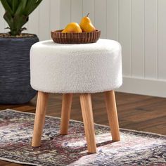 a white stool with two pears in a basket on top and a rug next to it