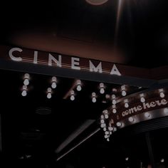 a sign that says cinema hanging from the ceiling in front of some lights and people