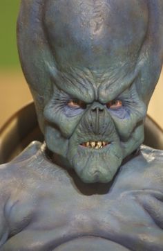 a close up of a man with an alien face and blue skin on his body