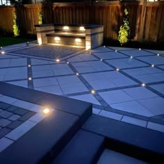 an outdoor patio with lights on it and steps leading up to the fire pit in the center