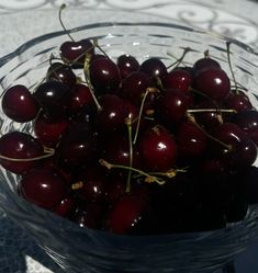 a glass bowl filled with cherries on top of a table