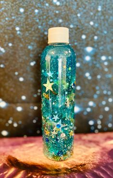 a water bottle with stars on it sitting on a table in front of a wall