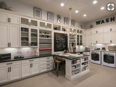 a large kitchen with white cabinets and black counter tops on the island in front of a washer and dryer