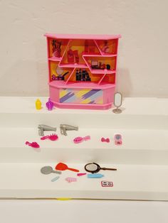 there is a pink toy shelf with various items on it, including scissors and combs