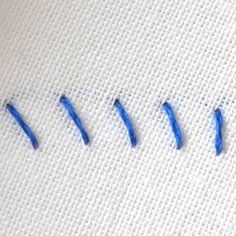 blue pins are on the side of a white piece of fabric that is stitched together