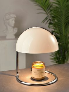 a table lamp with a jar of honey on it sitting next to a potted plant