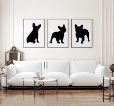 three black and white prints on the wall above a couch in a room with hardwood floors