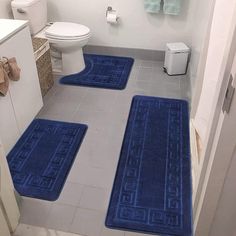 three blue bath mats in a bathroom next to a toilet