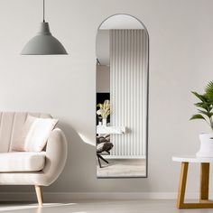 a living room with a white couch and large mirror on the wall next to it