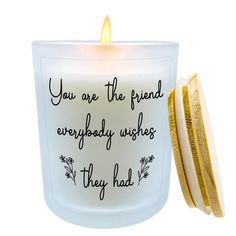 a white candle with a quote on it next to a gold rimmed container that says, you are the friend everybody wishes they had