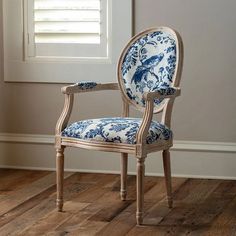 a blue and white chair sitting on top of a wooden floor next to a window