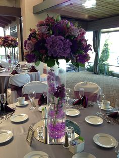 a vase filled with purple and white flowers on top of a table covered in plates