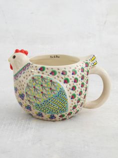 a ceramic mug with a rooster design on the front and sides, sitting on a white surface