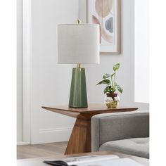 a table lamp sitting on top of a wooden table next to a gray couch and chair