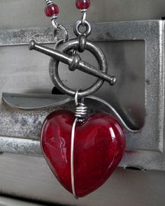 Ver. 9 // NEW: Larger heart pendant! Heart of darkness. Perfect gift for the not-so-girly-girl. Forget the sticky-sweet heart... this has edge. A gloriously-glossy glass heart pendant in sultry, regal red has been wrapped and bound in oxidized sterling silver wire and suspended from a gunmetal black toggle clasp and chunky antiqued silver plated chain. Please note that each heart is slightly different, but each one is gorgeous! NEW: Larger heart pendant! Deep red glass heart pendant: approx. 1" Heart-shaped Glass Jewelry For Valentine's Day, Glass Jewelry With Heart Charm For Valentine's Day, Heart-shaped Glass Necklace For Valentine's Day, Valentine's Day Jewelry With Heart Charm And Glass Material, Valentine's Day Heart-shaped Glass Necklace, Heart-shaped Glass Jewelry For Party, Valentine's Day Glass Jewelry With Heart Charm, Glass Heart Pendant Necklace For Gift, Valentine's Day Glass Necklaces Gift