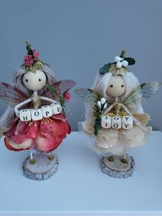 two little angel figurines sitting on top of a white table next to each other