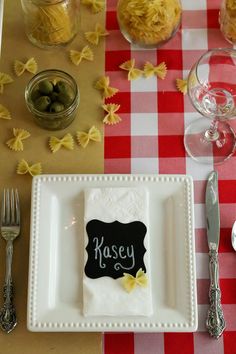 a place setting with pasta and olives on the table for guests to eat at