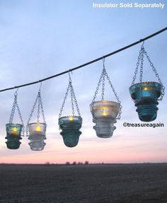 several hanging glass lanterns with lights on them in an open field at sunset or dawn