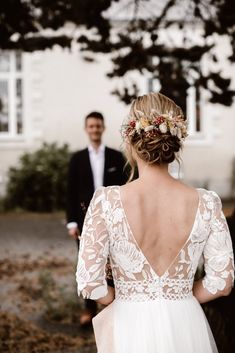 a man and woman standing next to each other in front of a building with trees