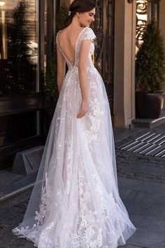 a woman in a wedding dress is walking down the street with her back to the camera