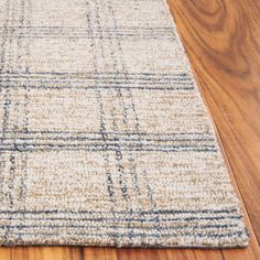 an area rug on the floor with wooden floors and wood planks in the background