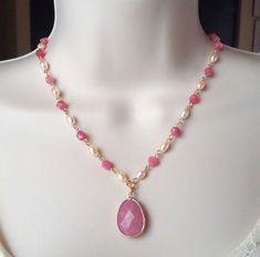 A beautiful necklace features a large Pink Rhodochrosite gemstone Pendant, hangs from a hand beaded chain consist of ivory freshwater pearls and Pink Rhodochrosite gemstones, all plated in 24 karat gold. This simple yet striking necklace is finished with a spring ring clasp. The necklace measures 16 inch in length, with 2 inches extension. Pendant measures 1 inch. Rhodochrosite is a stone that integrates physical and spiritual energies, stimulating love and passion while energizing the soul. Rho Spring Necklace, Pink Rhodochrosite, Gemstone Pendant Necklace, Gemstone Necklace Pendant, Hand Beading, Beaded Chain, Spring Rings, Pearl Beads, Gemstone Pendant