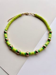 a green and gold beaded necklace sitting on top of a piece of white paper