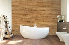 a white bath tub sitting on top of a wooden floor next to a toilet and sink