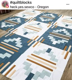 a large quilt is laying on the floor with it's border in blue and brown