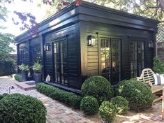 a small black building sitting in the middle of a garden