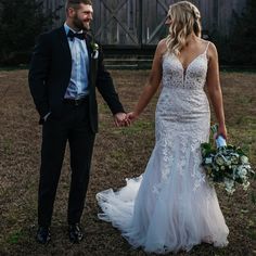 a bride and groom holding hands in front of a barn