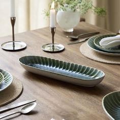 a wooden table topped with plates and silverware