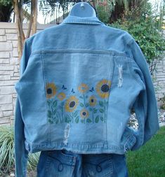 a jean jacket with sunflowers painted on it