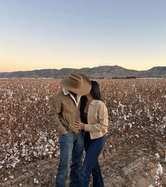 a man and woman standing in front of a cotton field