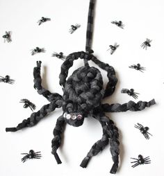 a spider made out of black yarn on a white surface with lots of small black bugs around it