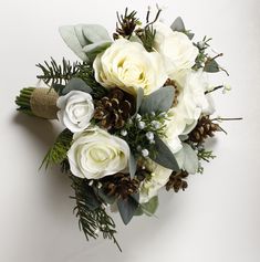 a bridal bouquet with white flowers and pine cones