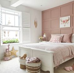 a bedroom with pink walls and white bedding in the corner, along with baskets on the floor