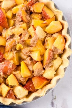 a pie crust filled with meat and fruit on top of a white countertop next to a blue towel