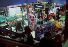 people are standing in front of a store selling drinks and confection products at night