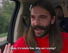 a man with long hair sitting in the back seat of a car talking to someone