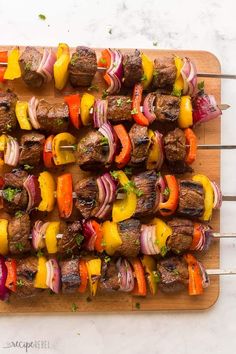 skewered steaks and vegetables on a wooden cutting board