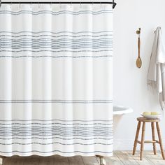 a bathroom with a white shower curtain and wooden stool