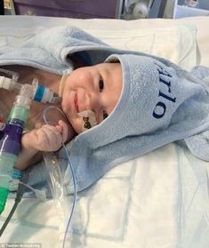 a baby laying in a hospital bed with an oxygen tube attached to it's head