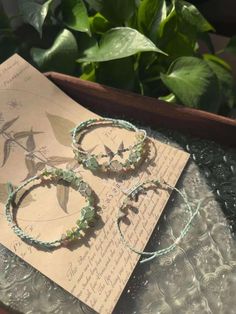 two green bracelets sitting on top of a piece of paper next to a plant