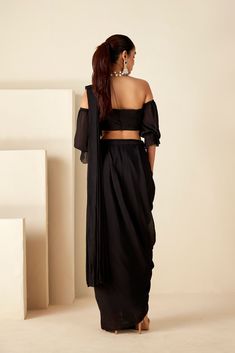 This pre-draped saree features exquisite hand-embroidered zardosi details, adding a touch of opulence to the off-shoulder style. Perfect for cocktail nights and sangeet ceremonies, it offers convenience with its pre-drape skirt saree design and back hook opening. The sheer sleeve details enhance its allure, while the luxurious georgette crepe fabric in timeless black ensures both comfort and sophistication. Make a statement at your special occasions with this stunning ensemble that effortlessly combines tradition and modernity. Elegant Festive Choli With Draped Sleeves, Elegant Evening Pre-draped Saree With Resham Embroidery, Elegant Designer Choli With Draped Sleeves, Designer Party Wear Saree With Draped Sleeves, Georgette Saree With Draped Sleeves For Evening, Elegant Pre-draped Saree With Resham Embroidery For Evening, Festive Party Wear Blouse With Draped Sleeves, Festive Party Wear Saree With Draped Sleeves, Elegant Traditional Wear With Traditional Drape For Evening