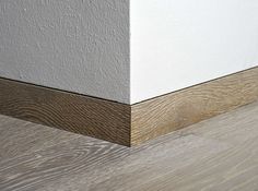 the corner of a room with white walls and wood flooring on top of it