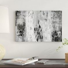 an abstract painting on the wall above a coffee table with a lamp and vase next to it