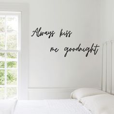 there is a wall decal that says always kiss me goodnight on the side of a bed